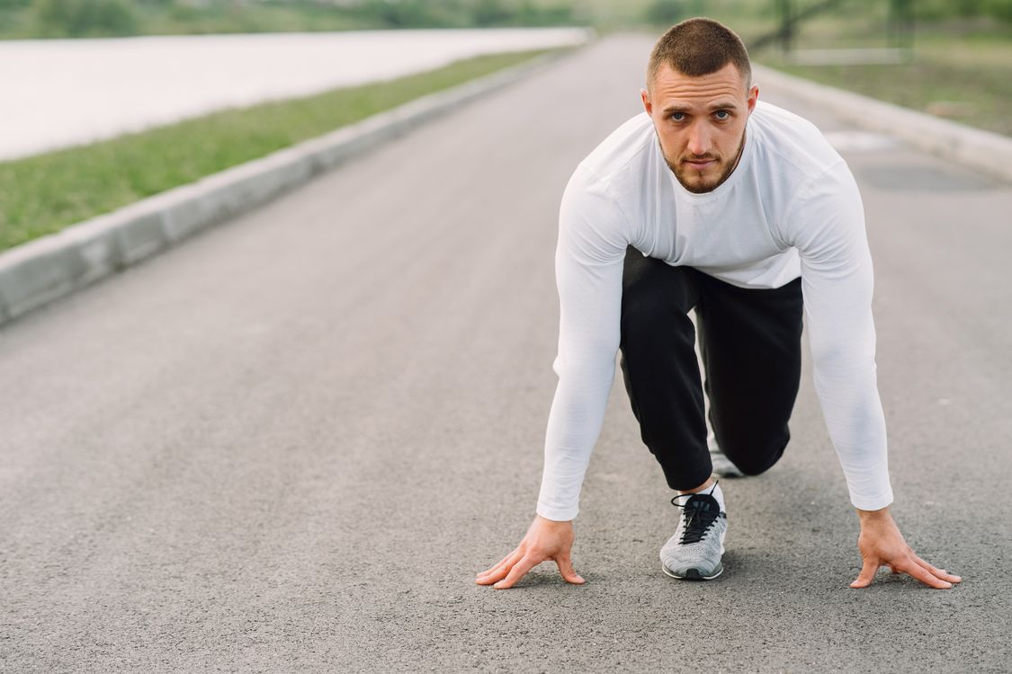 A man in sportswear preparing to run on an empty road